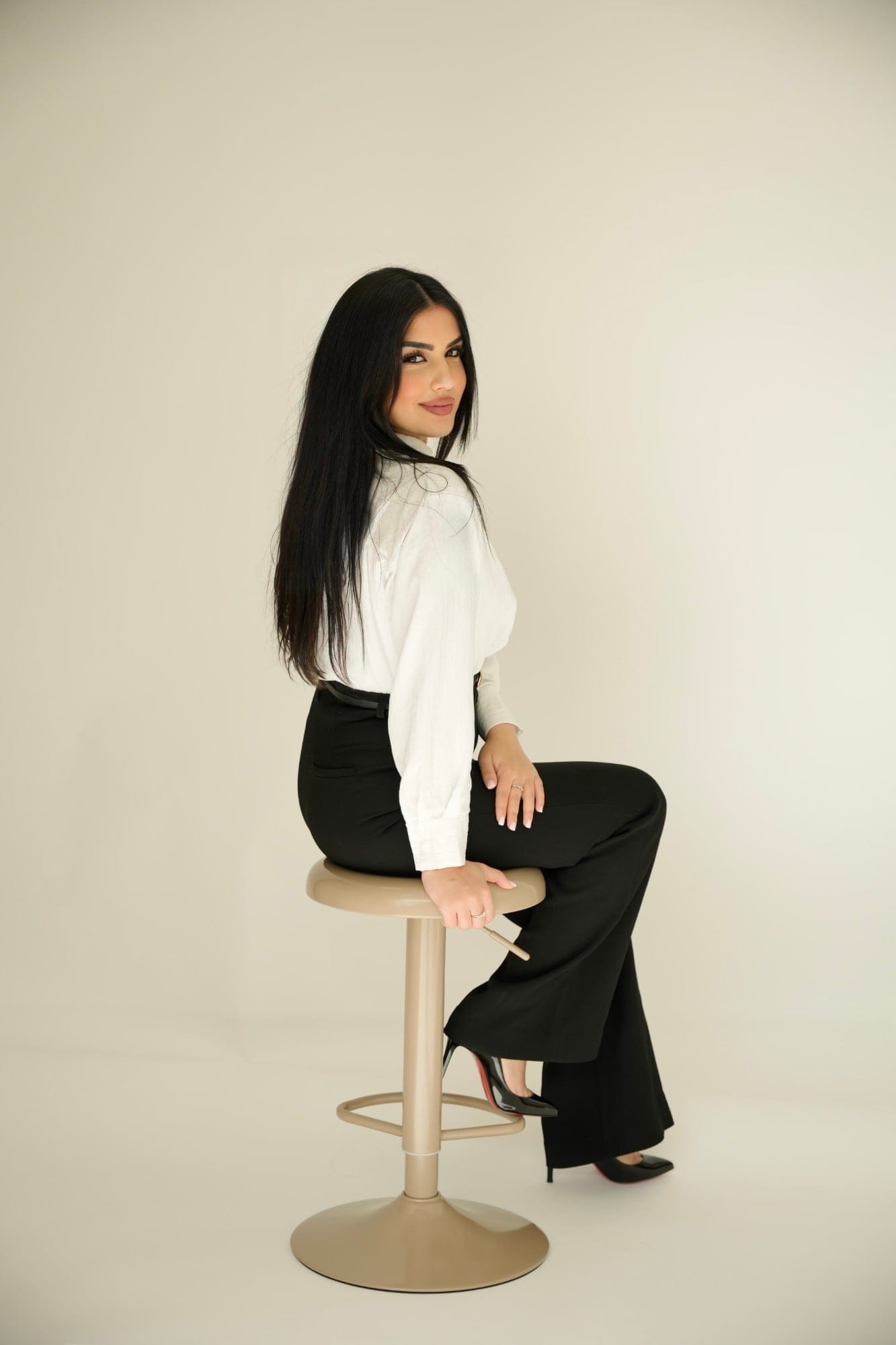 Sudaba, oprichter van Clinic Noord, op een kruk in de studio, in witte blouse